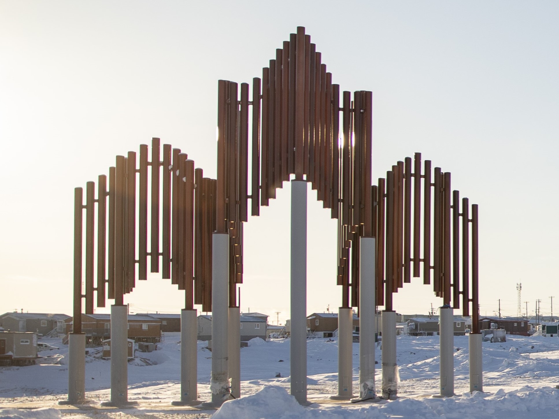 Photo of large art piece standing in snow made with vertical pipes that form a three-dimensional stylized maple leaf used in the design of the POLAR Star.